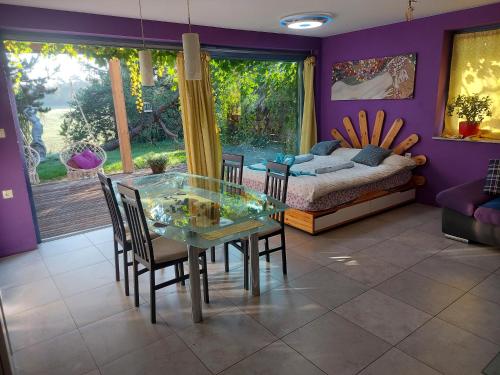 uma sala de jantar com uma mesa de vidro e cadeiras e uma cama em Guest House Bitter em Braslovče