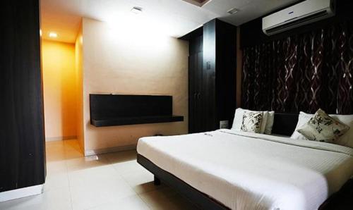 a bedroom with a bed and a flat screen tv at FabHotel Madurai in Udaipur