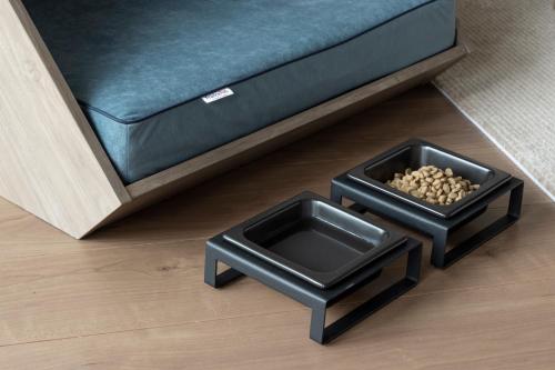 two black dog bowls sitting next to a couch at seven x seven Itoshima in Itoshima