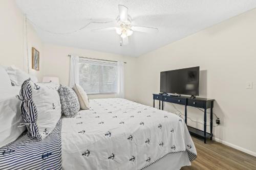 a bedroom with a bed and a flat screen tv at Coconuts Poolside #115 in Holmes Beach