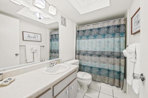 a white bathroom with a sink and a toilet at Coconuts Poolside #115 in Holmes Beach