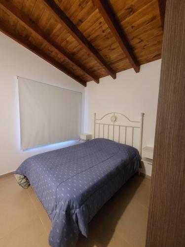 a bedroom with a bed with a blue comforter at El montañes in San Carlos de Bariloche