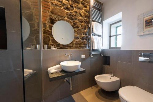 y baño con lavabo, aseo y espejos. en Medieval Cottage, en Monte San Savino