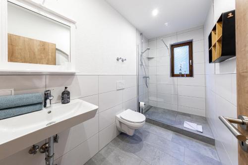 La salle de bains blanche est pourvue de toilettes et d'un lavabo. dans l'établissement Apartment Tea 1, à Triberg