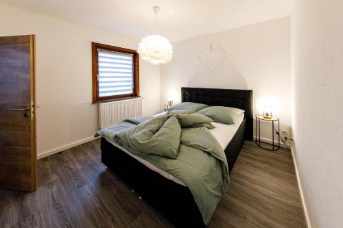 een slaapkamer met een bed met groene lakens en een raam bij Apartment Tea 1 in Triberg