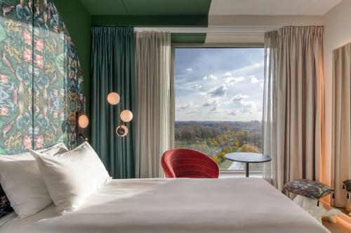 una camera d'albergo con un letto e una grande finestra di ibis Styles Rotterdam Ahoy a Rotterdam