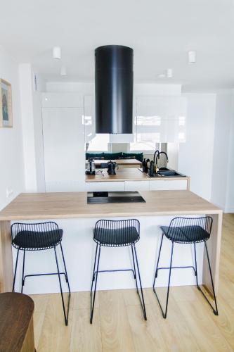 a kitchen with three bar stools and a counter at Apartamenty Parkowa 9 in Lesko