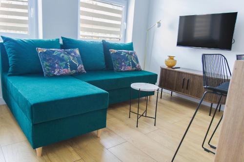 a blue couch in a living room with a television at Apartamenty Parkowa 9 in Lesko