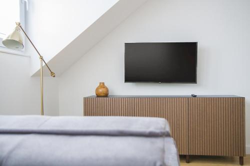 a bedroom with a tv on a white wall at Apartamenty Parkowa 9 in Lesko