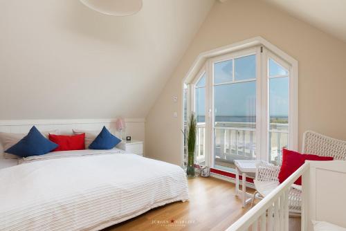a white bedroom with a bed and a large window at Strandhaus La Vela in Olpenitz
