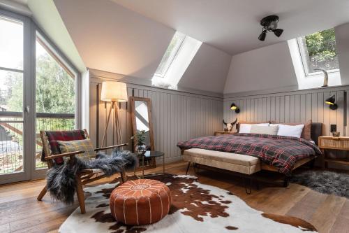 a bedroom with a bed and a chair and windows at Peaceful, Cozy Designer Mountain Studio in Harrachov