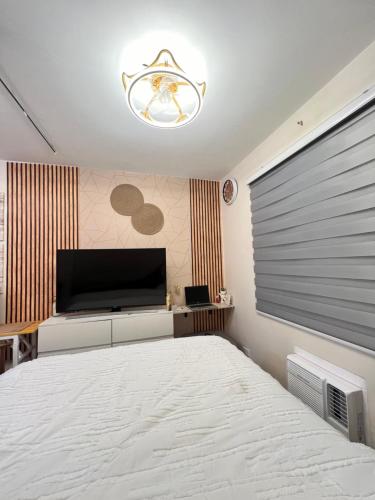 a bedroom with a large bed and a flat screen tv at Studio Unit-8 Spatial Condo in Davao City