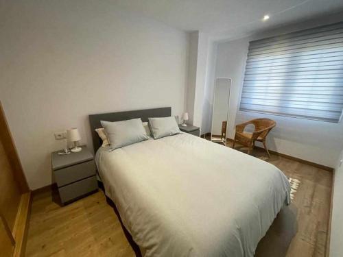 a bedroom with a large white bed and a window at Grupo Gontad Casa Secundino in Asalo