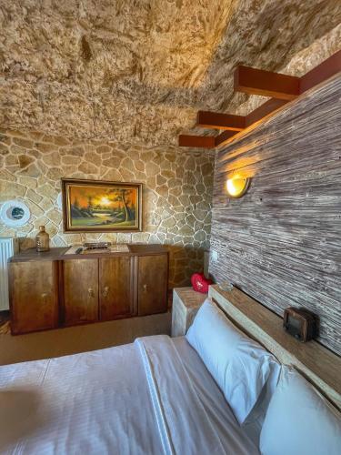 a bedroom with a bed and a stone wall at Anilia Guesthouse in Synikia Mesi Trikalon