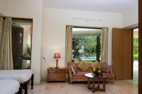a bedroom with a bed and a couch and a table at The Chitvan Resort in Ajmer