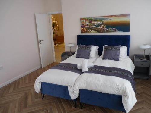 a bedroom with a blue bed and a painting on the wall at JTower Royal Suites - The Penthouse - Alefimmoed in Jerusalem