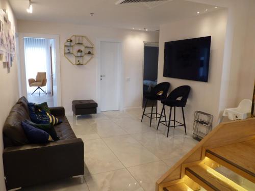 a living room with a couch and a tv at JTower Royal Suites - The Penthouse - Alefimmoed in Jerusalem