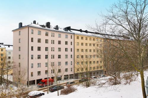 a large white building with cars parked in the snow at Nordic Studio near tram & metro 'Kallio' area in Helsinki