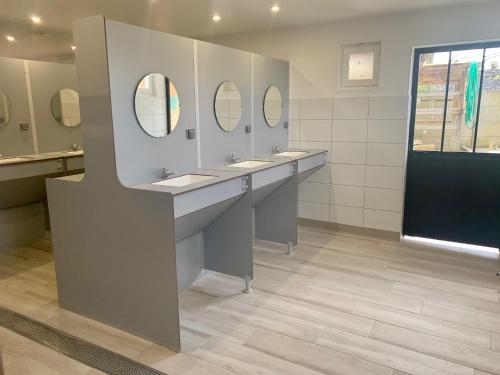 a bathroom with three sinks and two mirrors at Camping Les Pommiers in Sotteville-sur-Mer