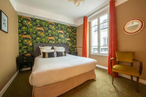 a bedroom with a large bed and a chair at Hôtel Des Batignolles in Paris