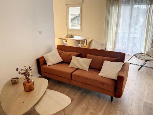 a living room with a brown couch and a table at Le Julia - Neuf - Gare et garage in Compiègne