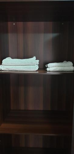 two white towels are sitting on a shelf at HOUSE IN AL AIN in Al Ain