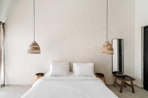 a bedroom with a white bed and two pendant lights at Hotel Anilevich Mansion in Beer Sheva