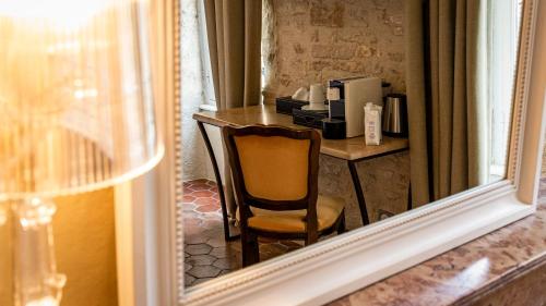 specchio che riflette una scrivania con sedia in una stanza di Les Remparts Hôtels et Demeures Historiques a Beaune