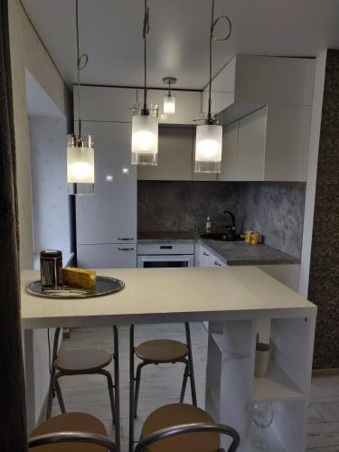 a kitchen with a counter with chairs and lights at Central cozy apartment in Kėdainiai