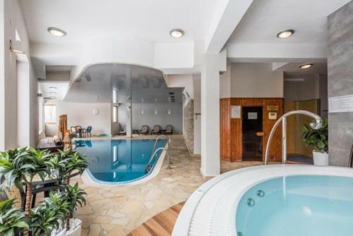 a large bathroom with a hot tub and a swimming pool at Apartament Szafran ApartamentyZakopianskie Basen Sauna Jacuzzi in Zakopane