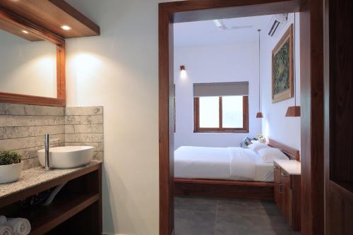 a bathroom with a sink and a bed in a room at Softouch Ayurveda Village Kerala in Kizhake Chālakudi