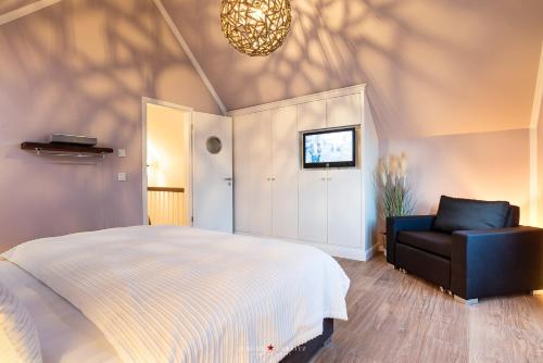 - une chambre avec un lit, une chaise et un lustre dans l'établissement Ferienhaus Auszeit, à Olpenitz