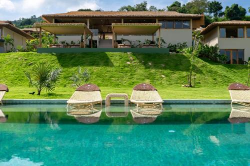 a house with a swimming pool with wicker chairs at Wild Cottages Elephant Sanctuary Resort in Amphoe Koh Samui