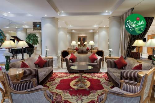 a lobby with couches and a table and a piano at Royal Manotel in Geneva
