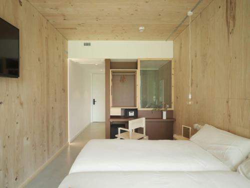 a bedroom with a white bed and a desk at Hotel Amiuka in O Pedrouzo