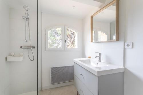 une salle de bain blanche avec un lavabo et une douche dans l'établissement La Maisonette Provençale Climatisée, à Aix-en-Provence