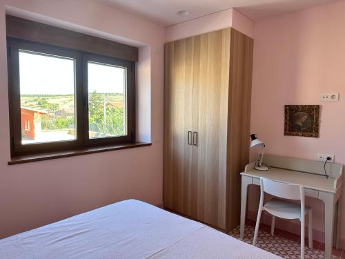 a bedroom with a desk and a bed and a window at La Casa Rosa in Burgos