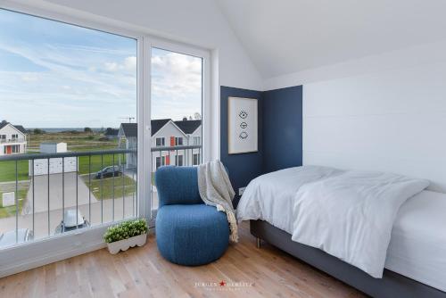a bedroom with a bed and a chair and a large window at Ferienwohnung Hafenkieker in Olpenitz