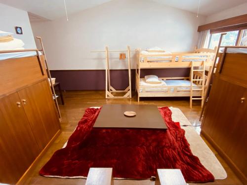 a room with two bunk beds and a red rug at Guest House Nishiborakan in Gujo