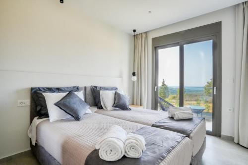 a bedroom with two beds and a large window at Aegean Sunset Villas in Mastichari