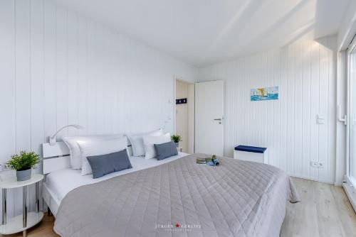 a white bedroom with a large bed in it at Wasserhaus Klabautermann in Olpenitz