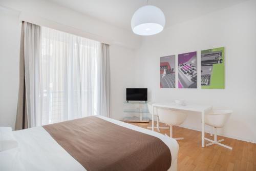 a bedroom with a bed and a desk and a television at Residence Hotel Grandi Magazzini in Nuoro