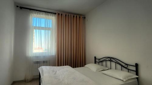 a bedroom with a bed and a window at Assalom Apartment 6 in Tashkent