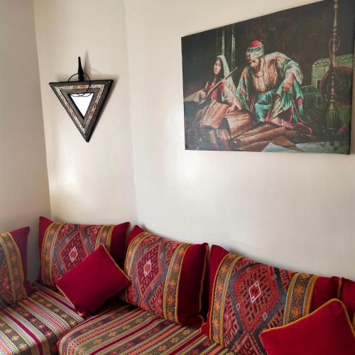 a living room with a couch and a painting on the wall at Belle appartement in Salé
