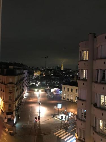 een stadsstraat 's nachts met gebouwen en straatverlichting bij Appartement vue sur Tour Eiffel à 5 min de Paris in Issy-les-Moulineaux