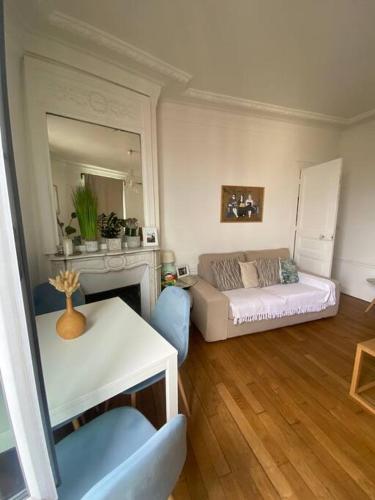 een woonkamer met een bank en een tafel bij Appartement vue sur Tour Eiffel à 5 min de Paris in Issy-les-Moulineaux