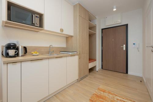 a kitchen with white cabinets and a brown door at Sun & Beach Apartments Bel Mare with Parking by Noclegi Renters in Międzyzdroje