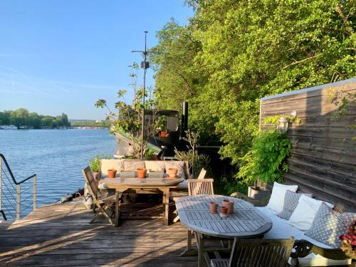 a wooden deck with a table and chairs next to the water at Péniche Suresnes in Suresnes