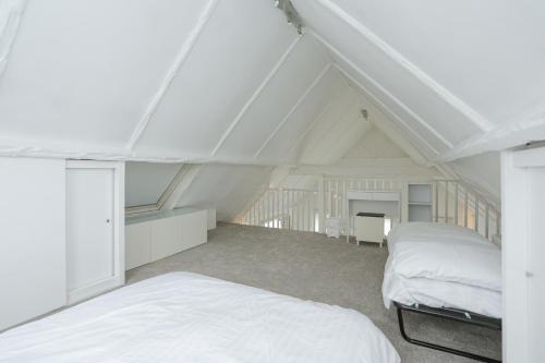 a attic bedroom with two beds and a table at Secret Seaside Retreat in Kent