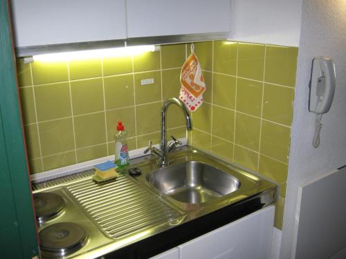 a sink in a small kitchen with green tiles at Ferienwohnung Roland in Balderschwang
